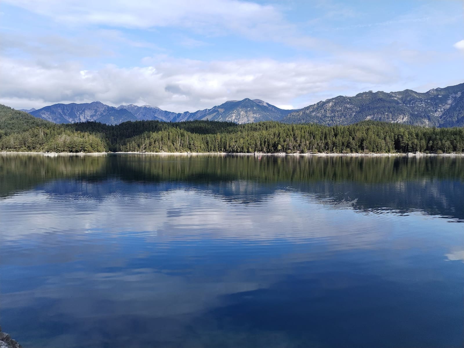 Der Eibsee mit klarem Wasser, bewaldetem Ufer und dem Wettersteingebirge am Horizont