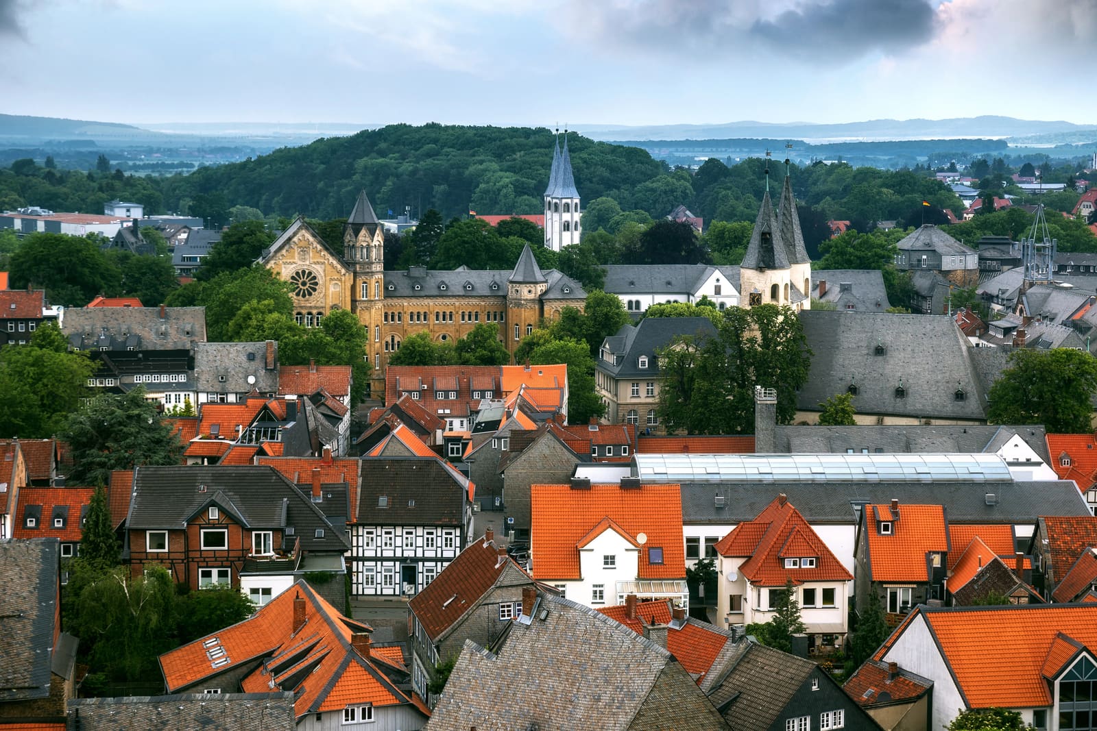 Panorama über Fachwerkhäuser und Ziegeldächer der Goslarer Altstadt mit mehreren Kirchtürmen und bewaldeten Harzhöhen