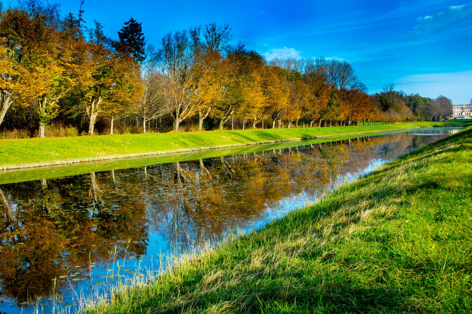 Herbstlich gefärbte Baumallee, gespiegelt im Grand Canal von Herrenchiemsee.
