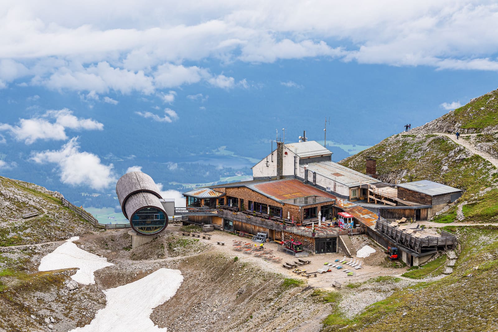 Bergstation der Karwendelbahn bei Mittenwald in felsiger Hochgebirgslandschaft mit Schneefeldern und Wanderweg