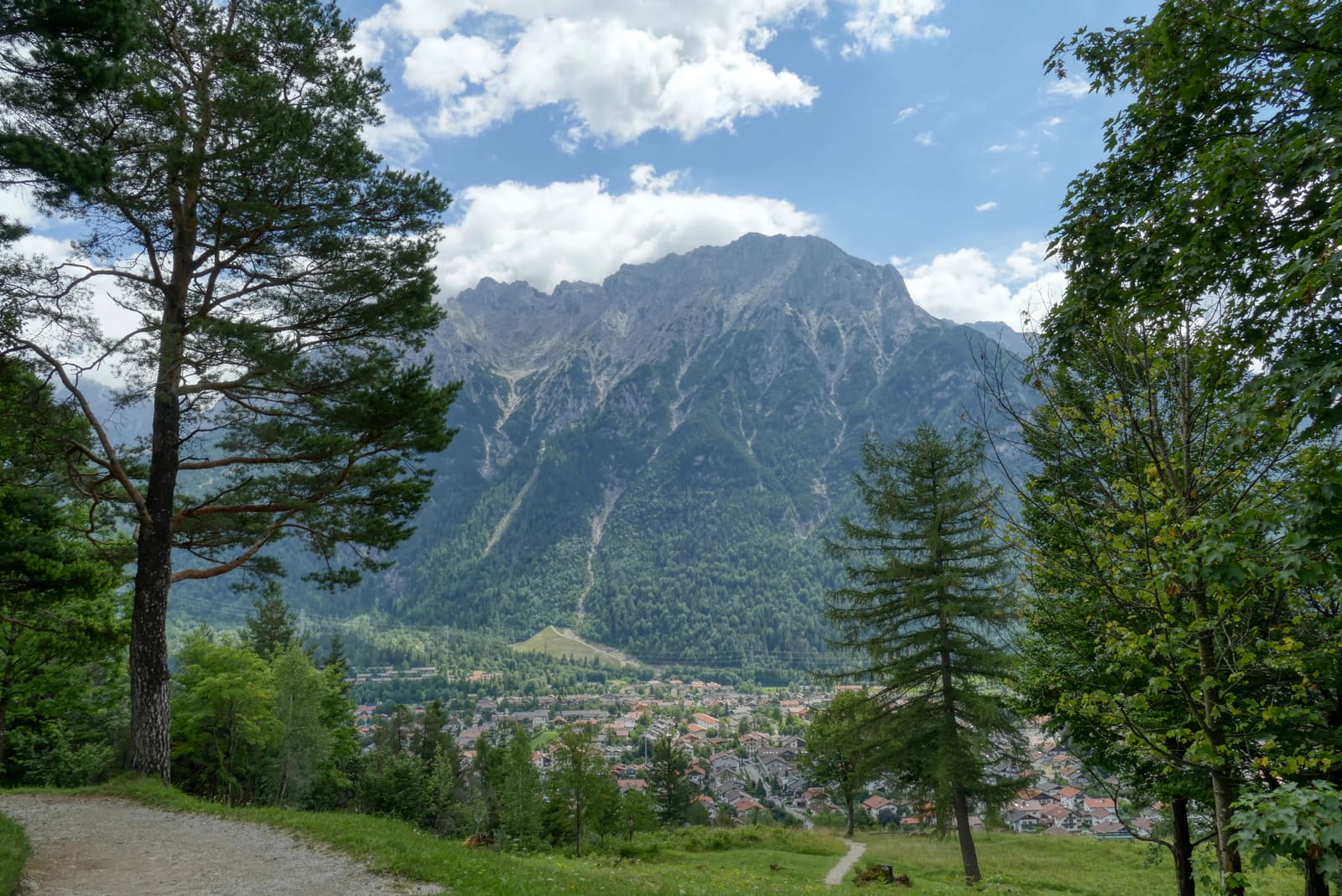 Wanderweg oberhalb von Mittenwald mit Blick auf den Ort und die steilen Felswände des Karwendels