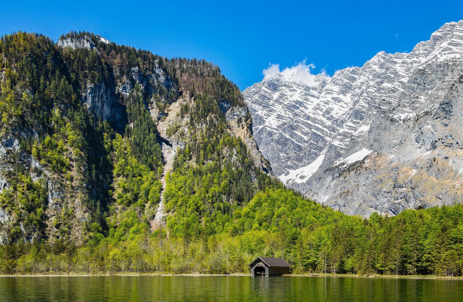 Ein hölzernes Bootshaus am Obersee vor den steilen Bergen des Nationalparks Berchtesgaden