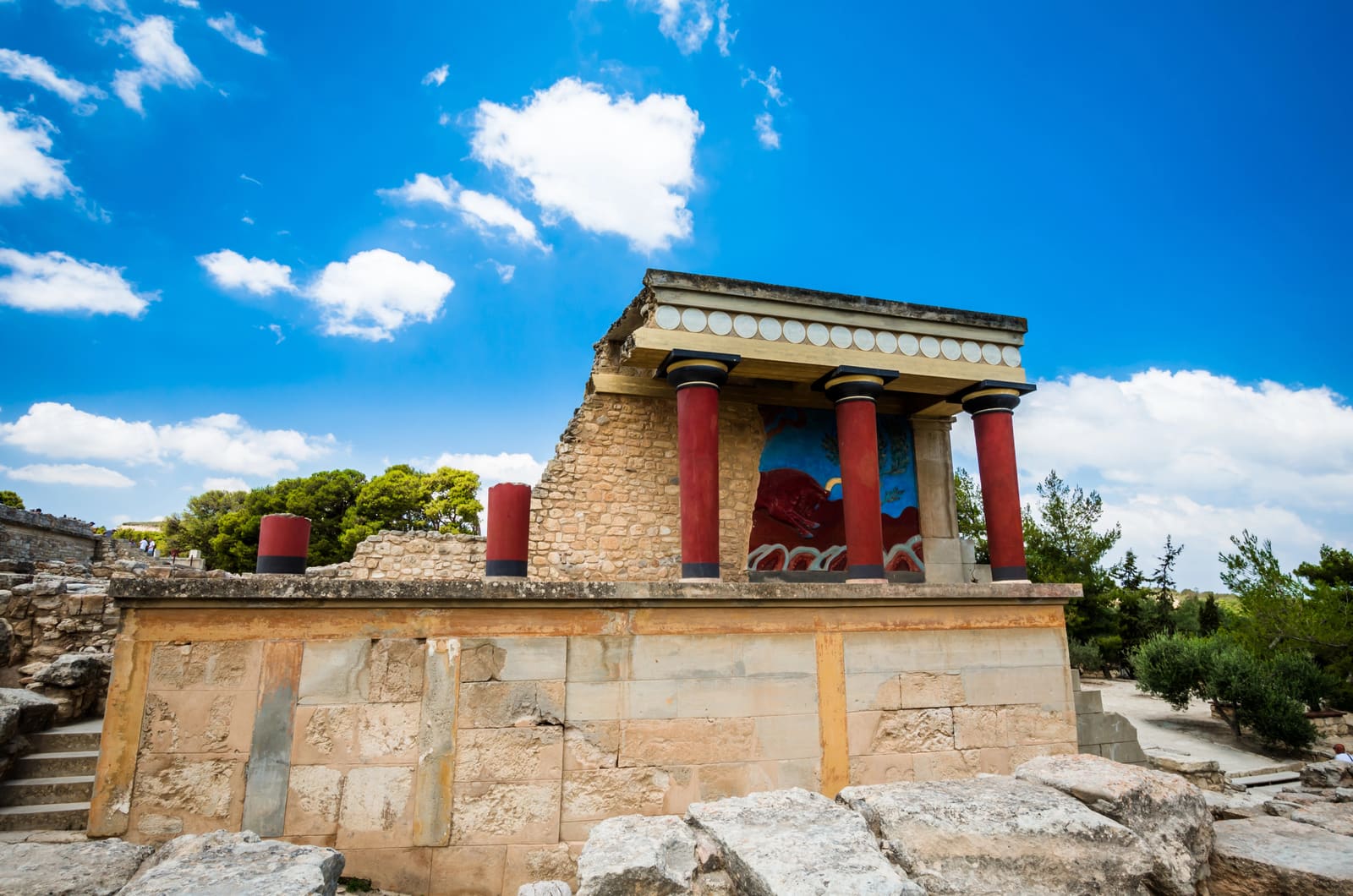 Rekonstruierte rote Säulen und ein Freskenbild im archäologischen Palastareal von Knossos auf Kreta