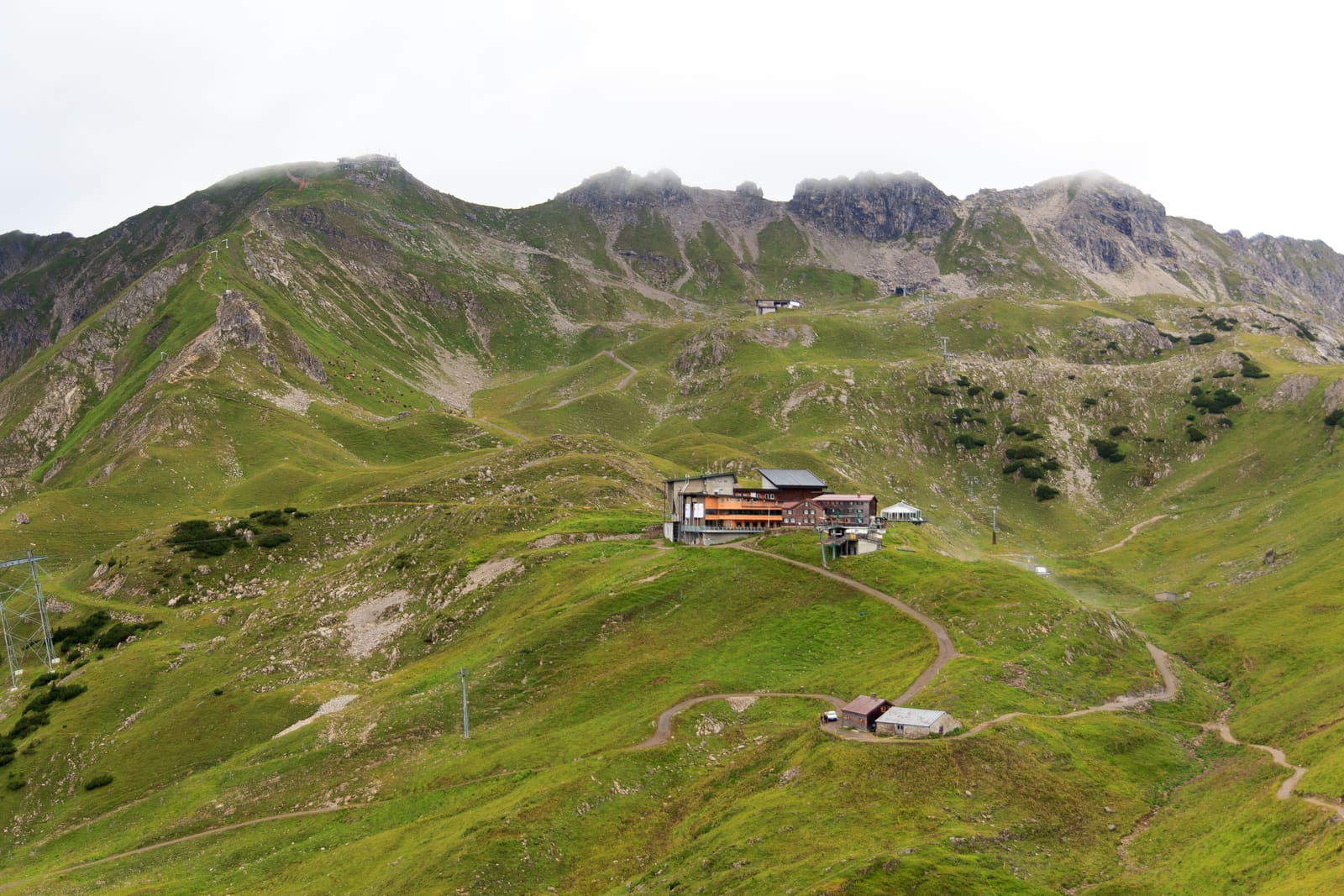 Seilbahnstation am Nebelhorn zwischen grünen Alpwiesen, Wanderwegen und felsigen Gipfelgraten unter tiefen Wolken