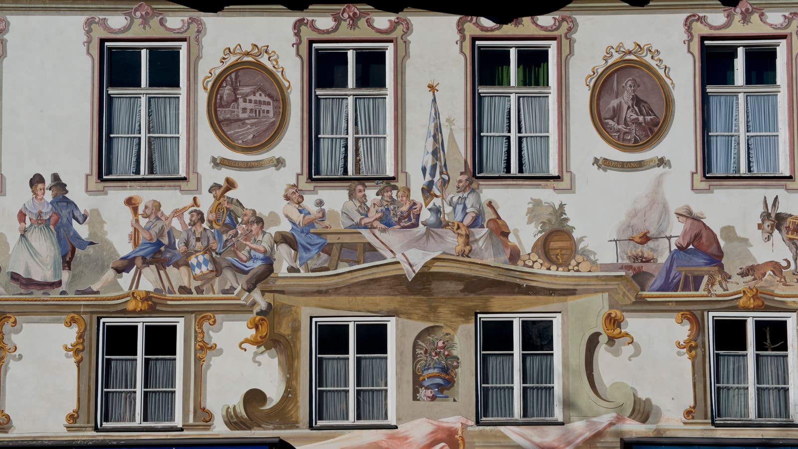 Detail einer Hausfassade in Oberammergau mit farbenreicher Lüftlmalerei und historischen Dorfszenen