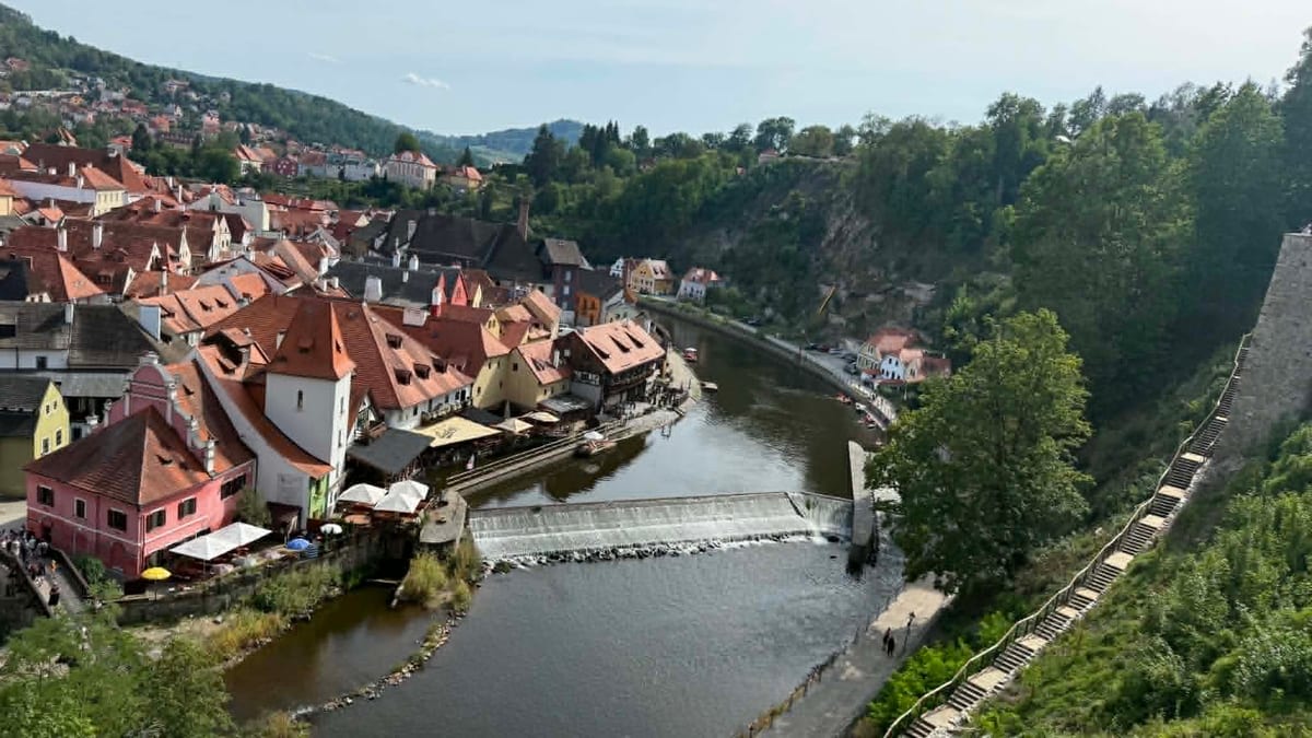 Blick von der Schlossterrasse in Český Krumlov über die Moldauschleife auf die roten Dächer der Altstadt und das Wehr unterhalb der Barbierbrücke